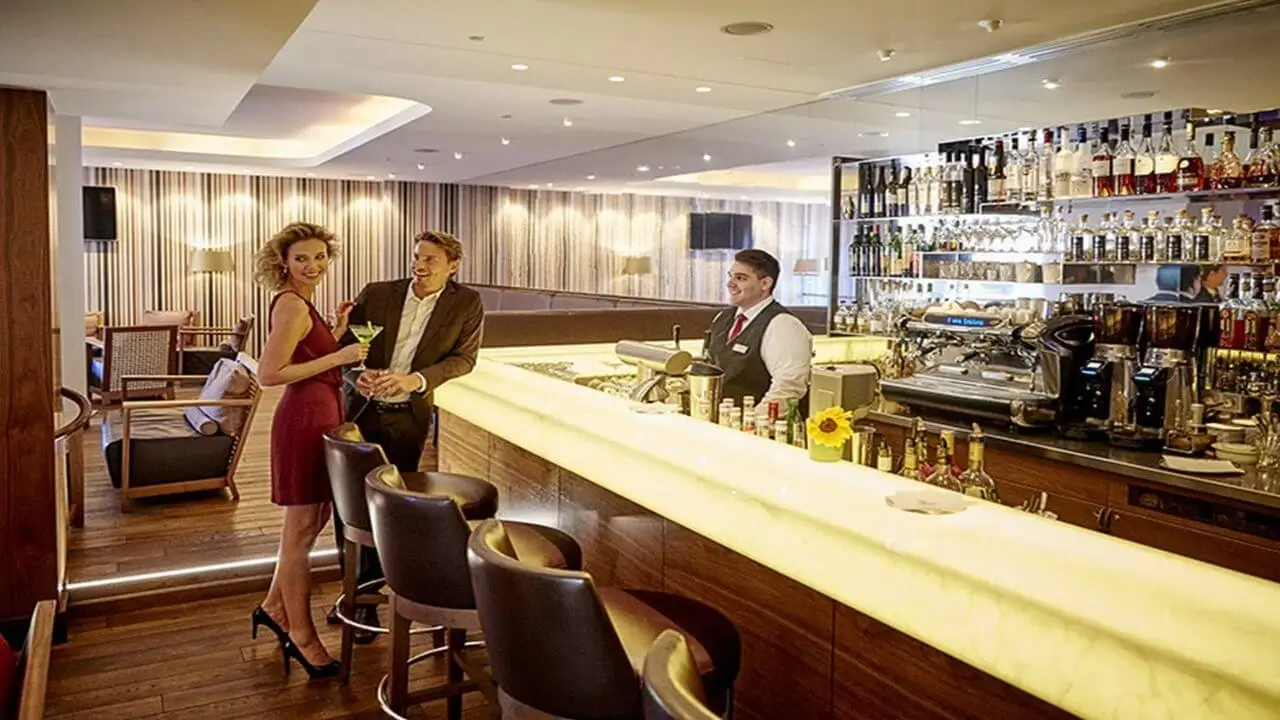 Paar in eleganter Bar bestellt Cocktails beim Barkeeper, moderne Einrichtung und entspannte Atmosphäre.
