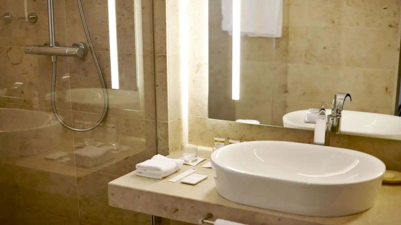 Ein modernes Badezimmer mit einem eleganten Waschbecken, einer Dusche und beleuchtetem Spiegel.