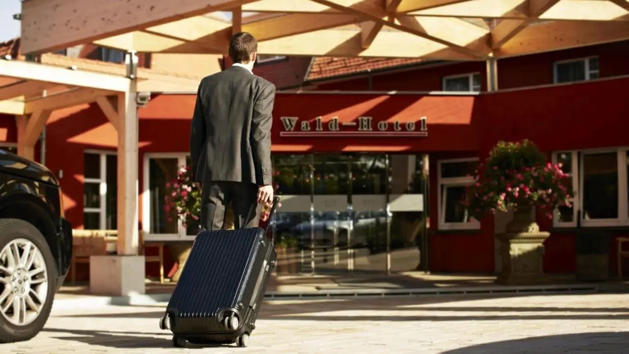 Ein Geschäftsreisender mit einem Koffer vor einem Hotel mit Tagungsraum Stuttgart.