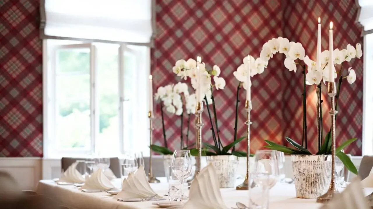 Festlich gedeckte Hochzeitslocation in Stuttgart mit weißen Stuhlhussen, silbernen Kerzenständern und Blumengestecken in einer hellen, eleganten Atmosphäre.