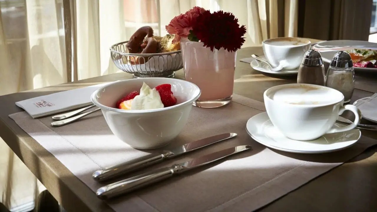 Ein stilvoll gedeckter Frühstückstisch mit Kaffee, Obst und frischen Backwaren.