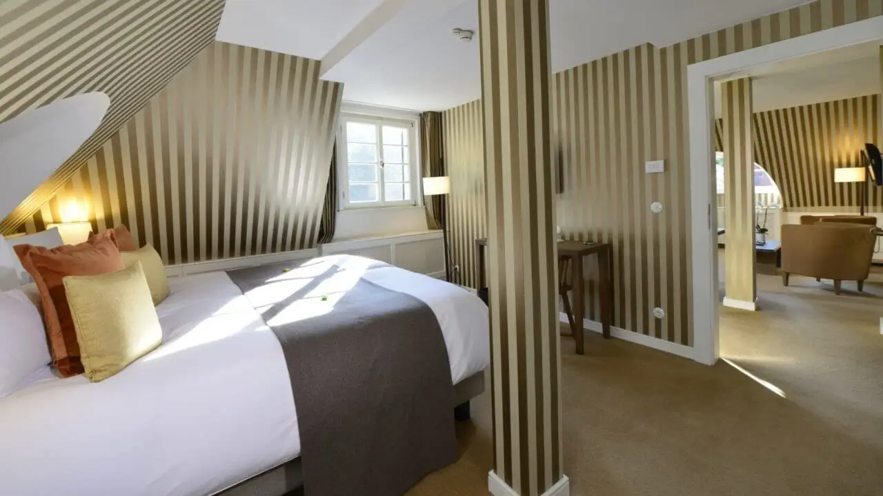 Eine geräumige Hotelsuite mit gemütlichem Schlafzimmer, stilvollen Möbeln und natürlichem Licht.