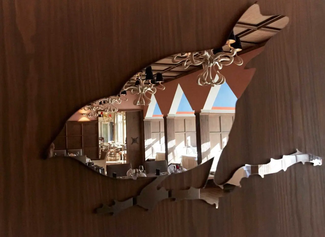 Spiegelung eines stilvollen Gourmet Restaurants in Stuttgart in einem vogelförmigen Ausschnitt eines Holzpaneels.